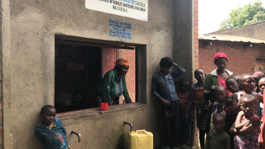 In Ruanda nimmt eine Frau Wassergebühren entgegen. Das Geld wird in die Gemeinde reinvestiert.